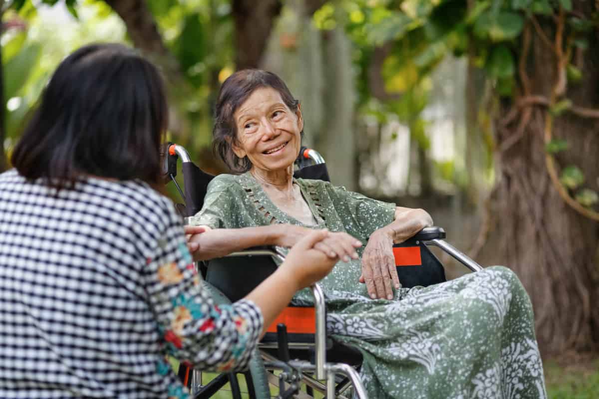 Elderly woman on wheelchair at home with daughter take care